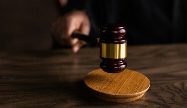 A gavel striking a sound block, symbolizing justice and legal authority in a courtroom setting.