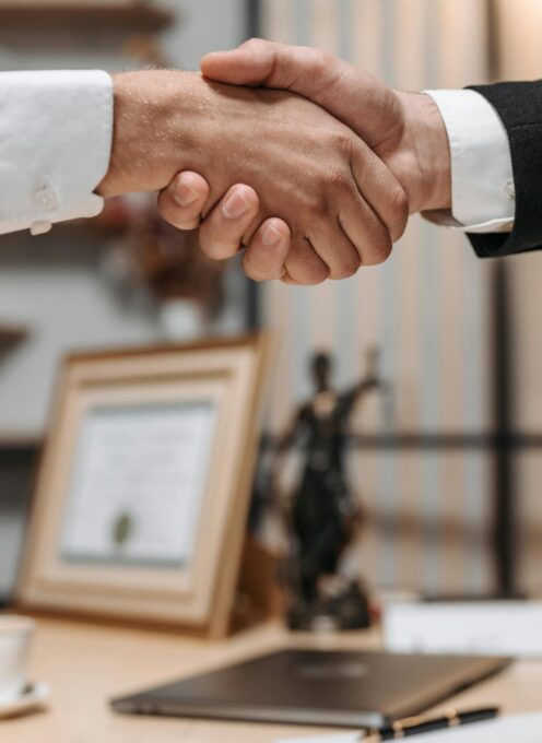 Close-up of a handshake between two professionals in a modern office setting, emphasizing partnership and agreement.