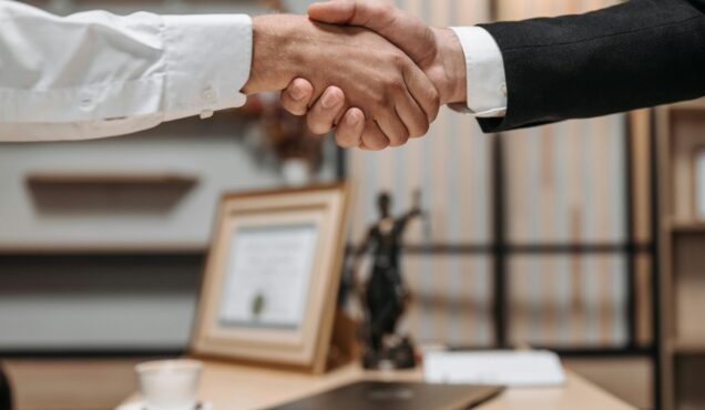Close-up of a handshake between two professionals in a modern office setting, emphasizing partnership and agreement.